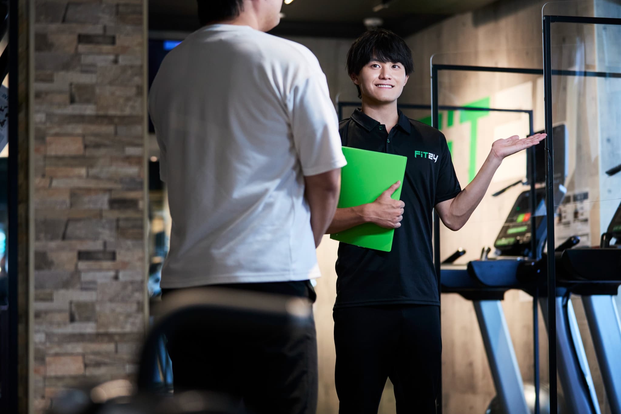 マシンを紹介しているジムスタッフの画像