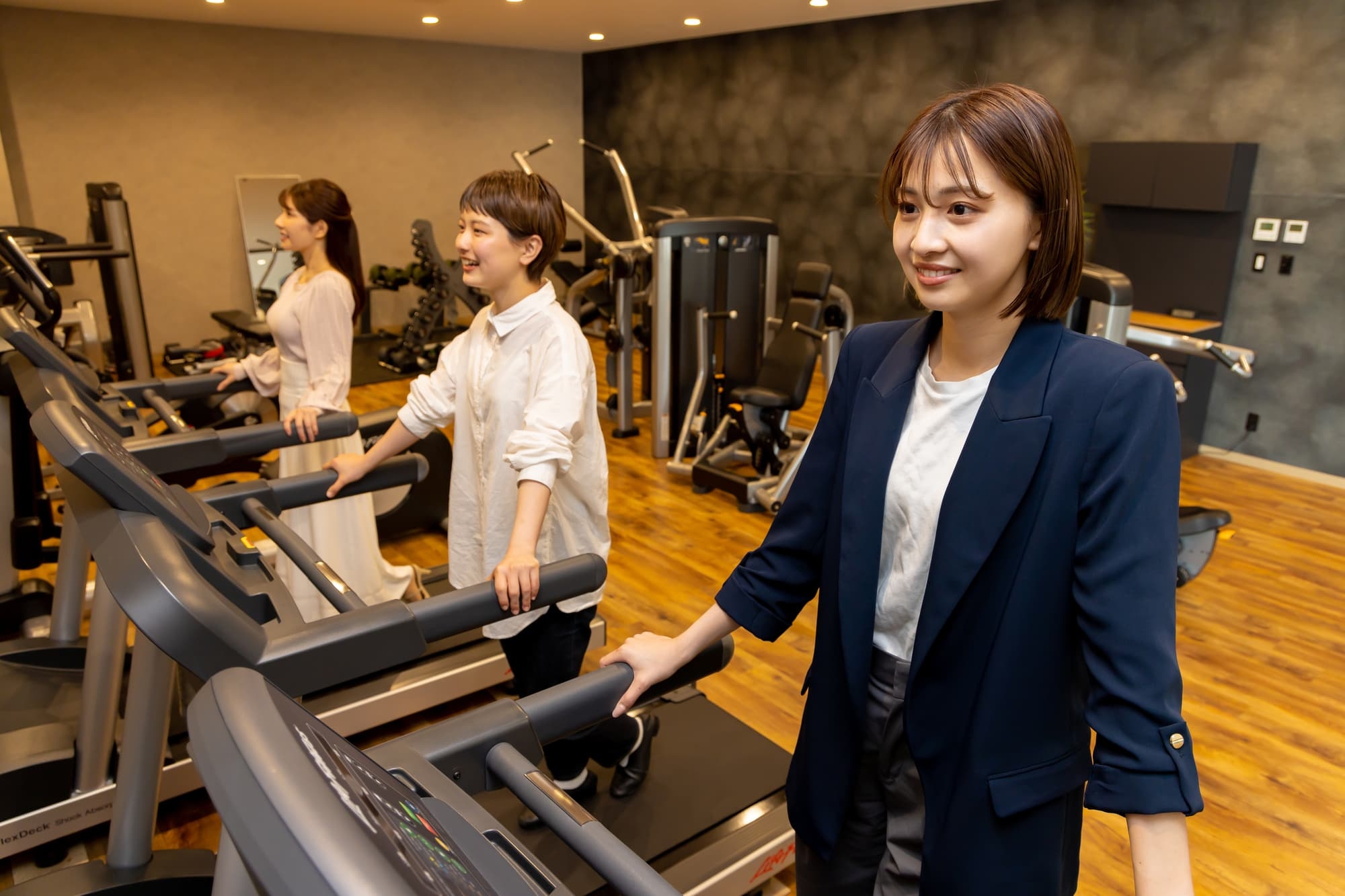 私服でトレッドミルに乗る女性たちの画像